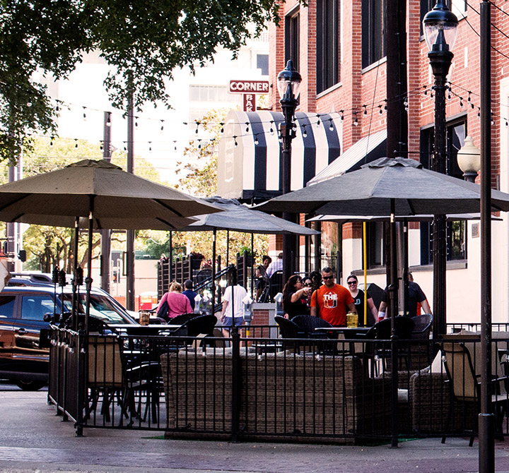 Outdoor cafe seating with umbrellas and people.