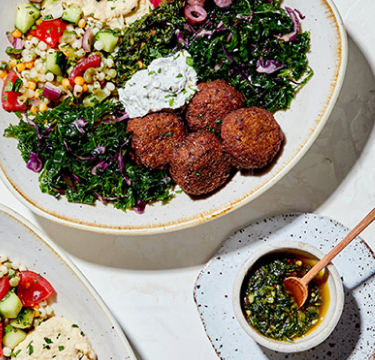 Delicious Mediterranean food (Falafel, Tabouli, Hummus, etc..) in  serving plates on a table.